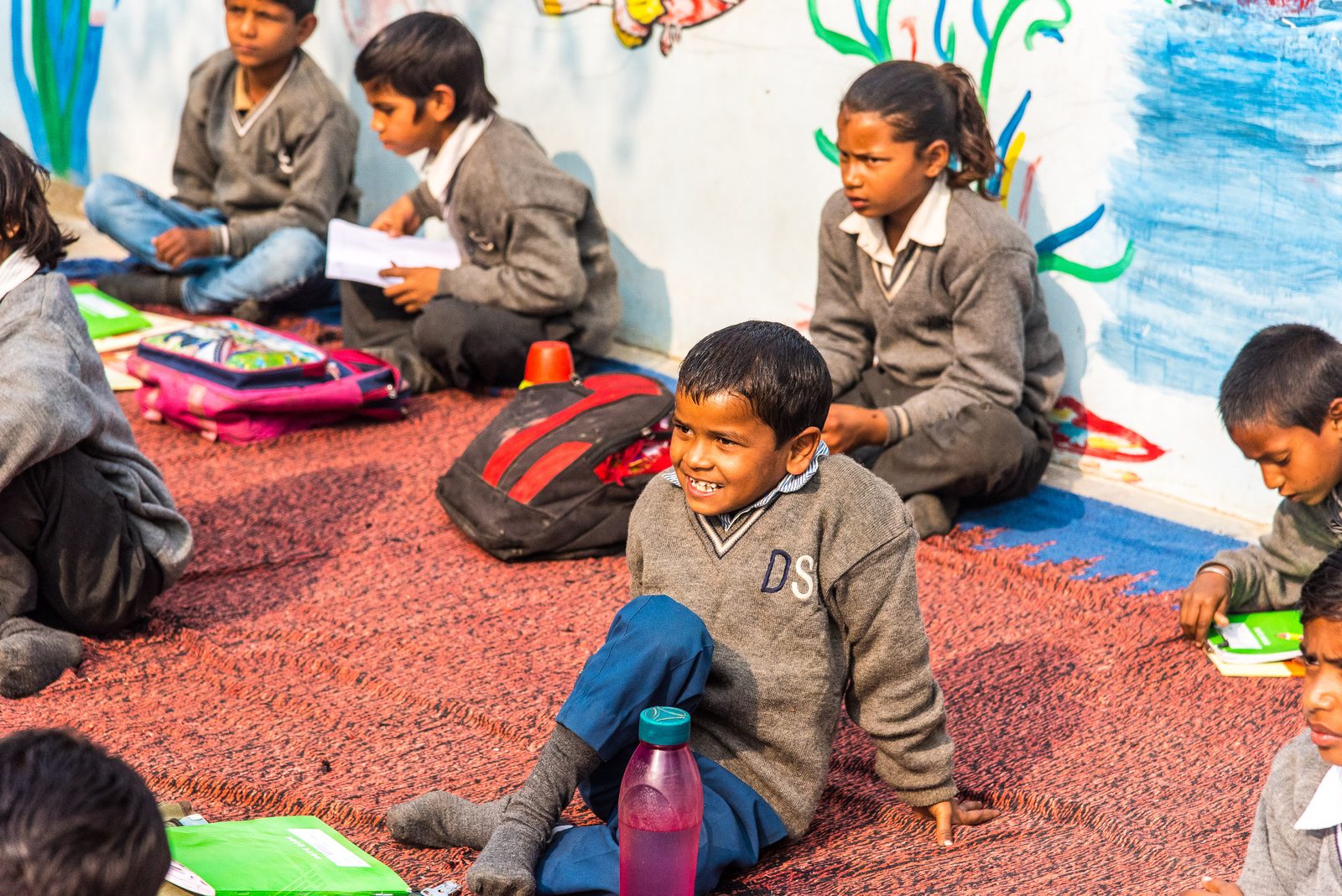 Children studying together on a mat at an open-air One Life At A Time class